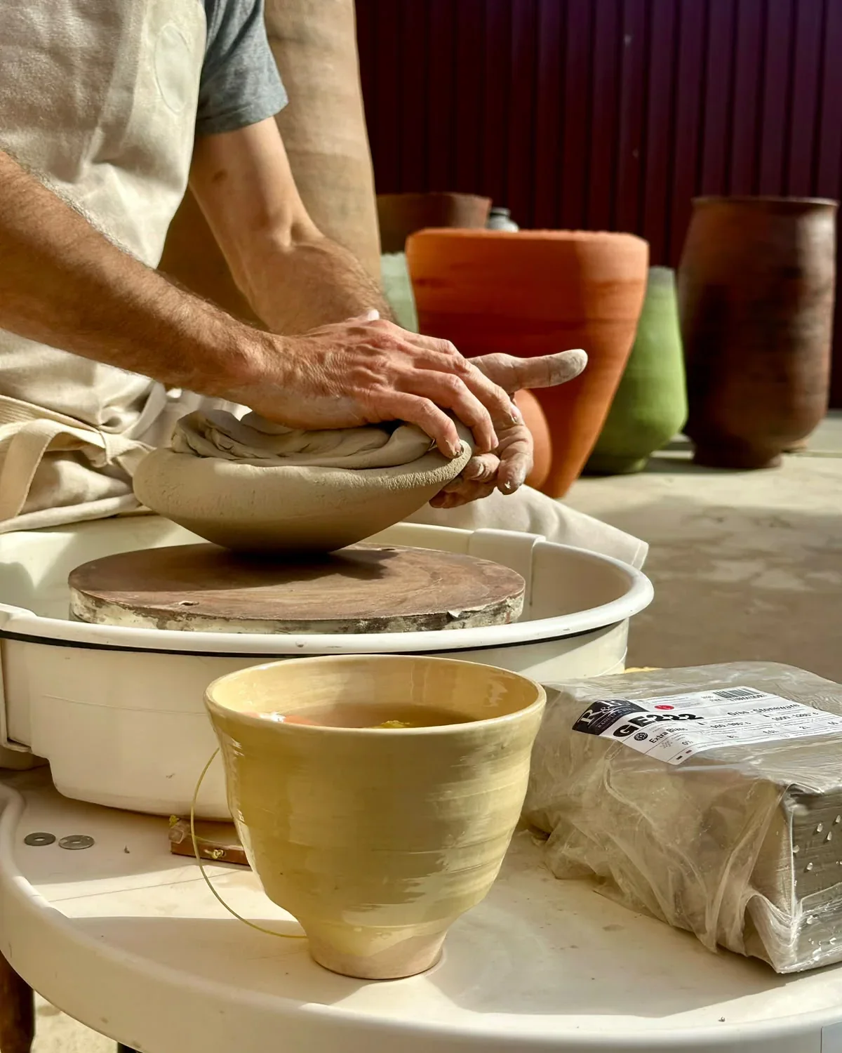 Mani che lavorano GE222 cruda sul tornio da ceramica