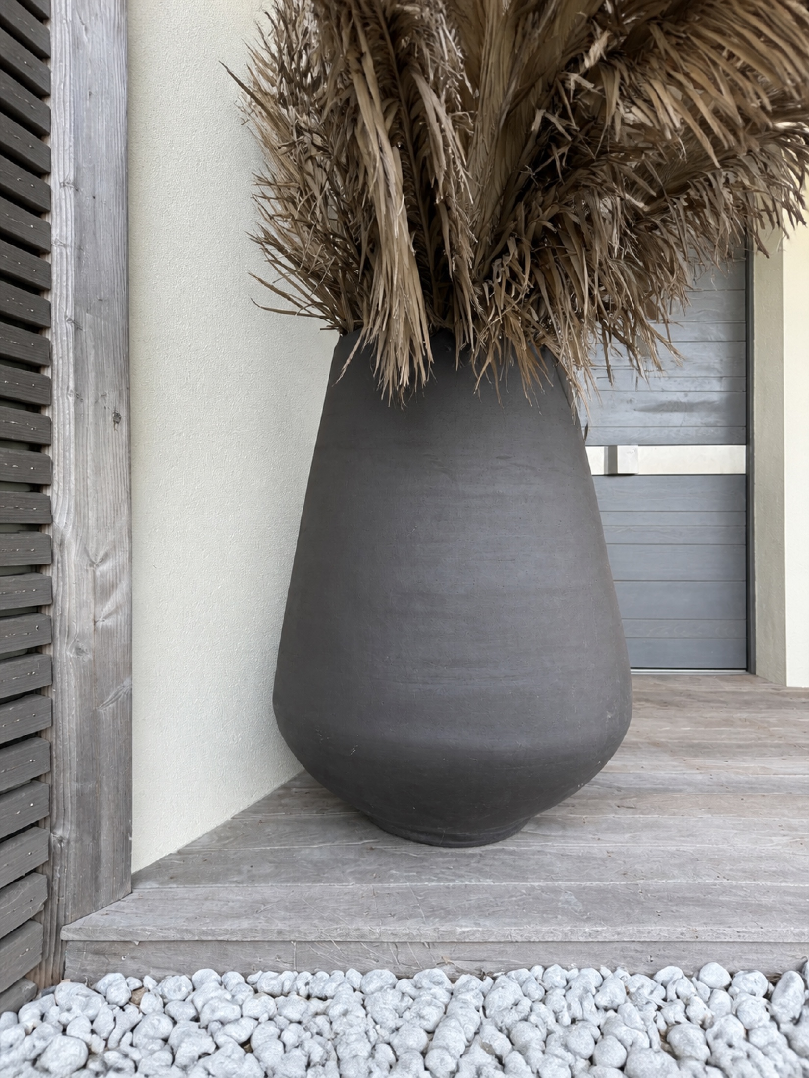 Grand vase Anthra GE700 avec palmes séchées sur sa terrasse contemporaine nettoyée